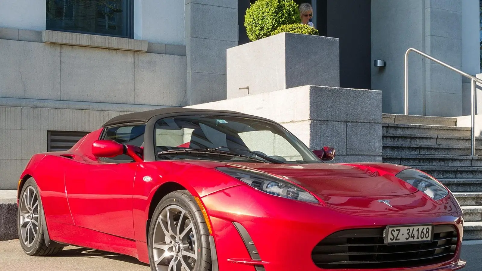 Tesla Roadster vermelho de primeira geração, parado em uma rua