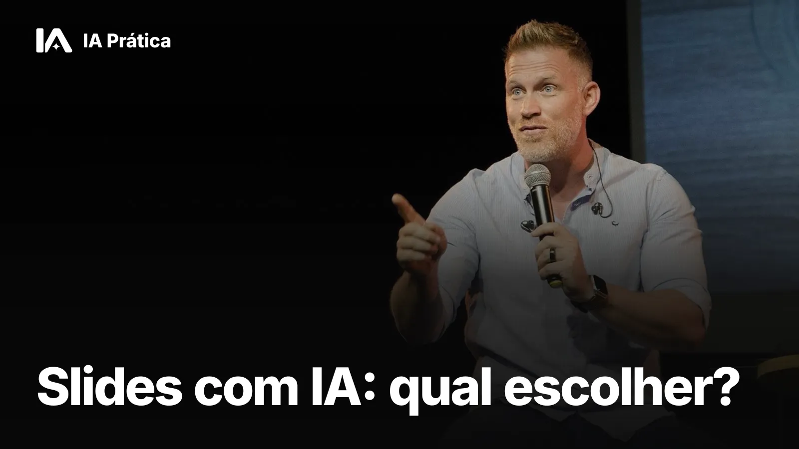 Palestrante de camisa clara falando ao microfone e apontando para a plateia, em um palco escuro